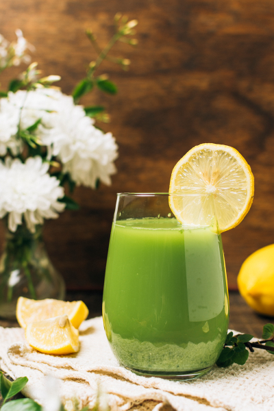 green juice with lemon slice and white flowers in background