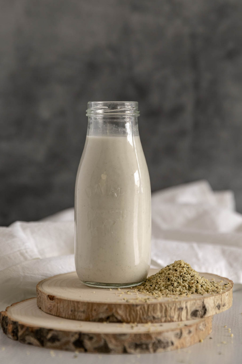 Bottle of hemp milk with scattered hemp seeds