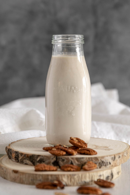 Bottle of pecan milk with scattered pecans