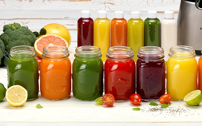 Row of various colored juices in mason jars.