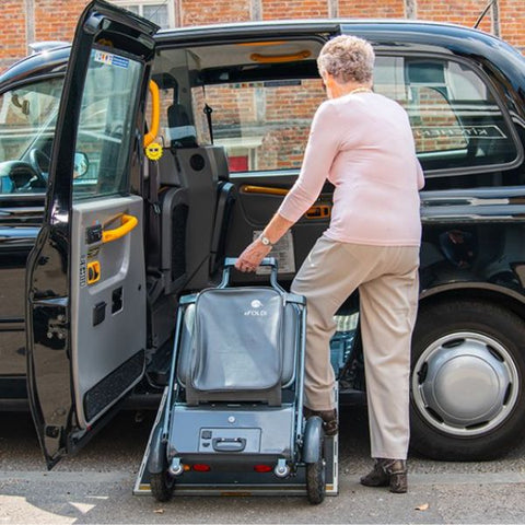 Lady putting the folded eFOLDi Explorer Ultra Lightweight Mobility Scooter in the back seat area of a car