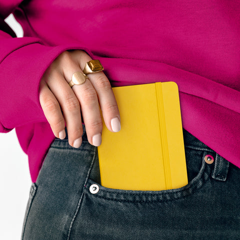 Female hand putting a small iPhone sized journal into her front pocket.