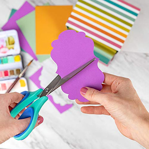 Paperage scissors being used to cut a decorative paper embellishment.
