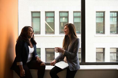 Two happy women sitting by the window