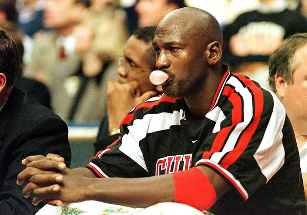 Michael Jordan chews bubblegum while sat on a bench.