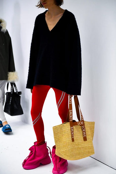 Model wears an oversized sweater, pink leggings and pink leather boots at Loewe's SS23 presentation for Paris Fashion Week