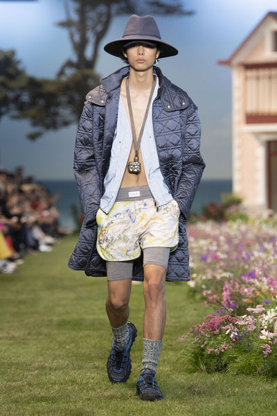 Model wears a waterproof parka, shorts and sneakers at Dior's SS23 presentation for Paris Fashion Week