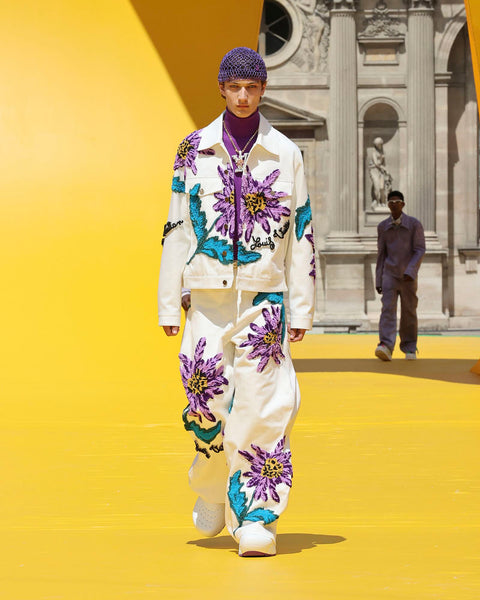 Model wears a cream and purple floral denim outfit at Louis Vuitton's SS23 presentation for Paris Fashion Week