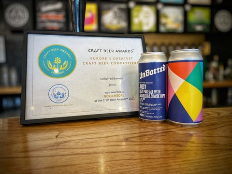 Two cans of Joosy next to award in a frame