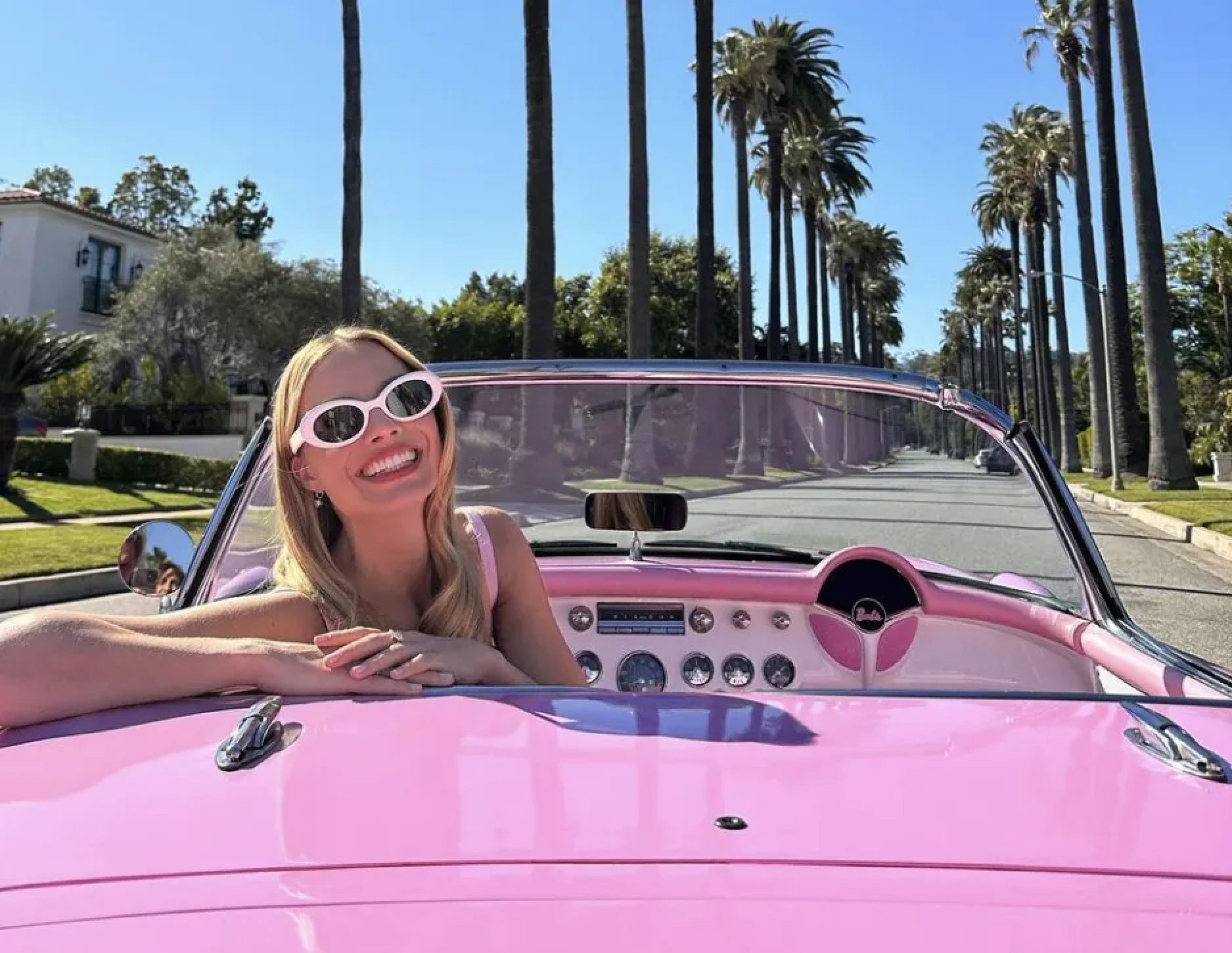 Margot robbie con outfit de Barbie en carro descapotable