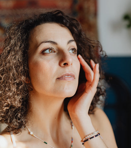 Woman examining her skin in the mirror, representing menopausal skin changes