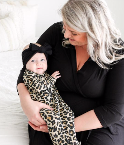 Baby in leopard outfit with mom holding her in a coordinating black outfit