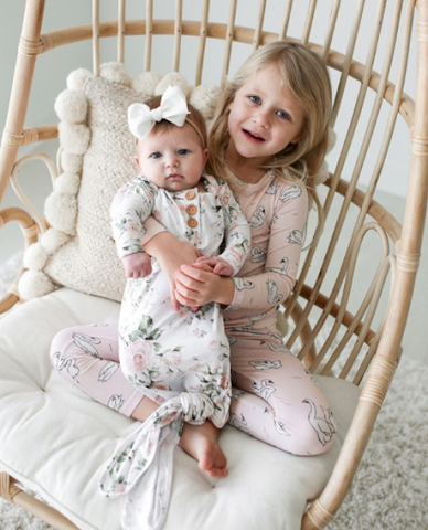 Baby in older sisters arms in matching outfits