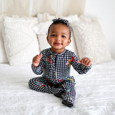 baby sitting up in girls one piece pajamas