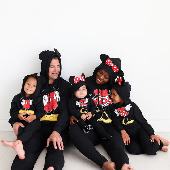 family sitting together wearing matching Mickey Mouse hoodies