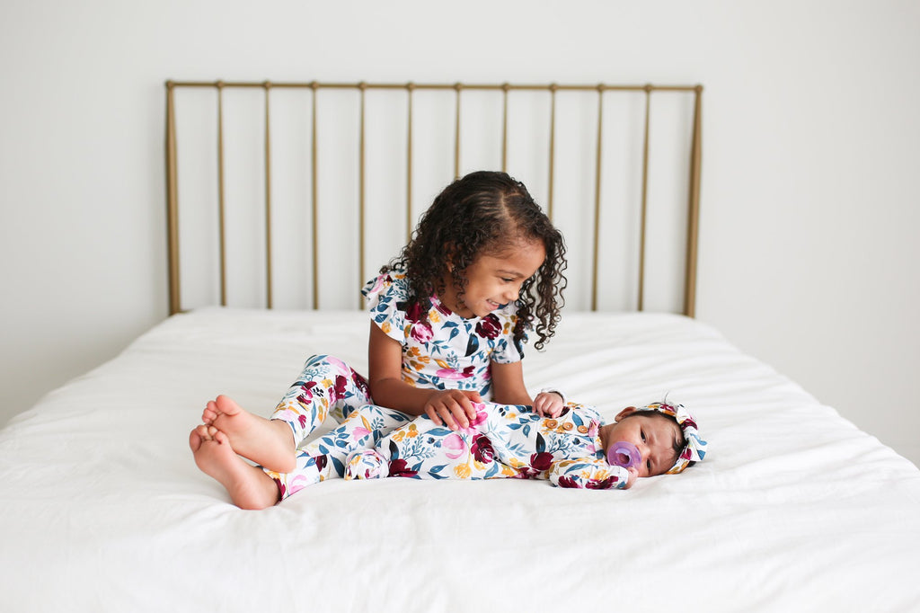 baby in newborn knotted gown, sister in matching floral print