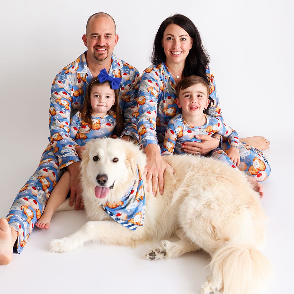 Family in matching Hanukkah pajamas sitting with dog 