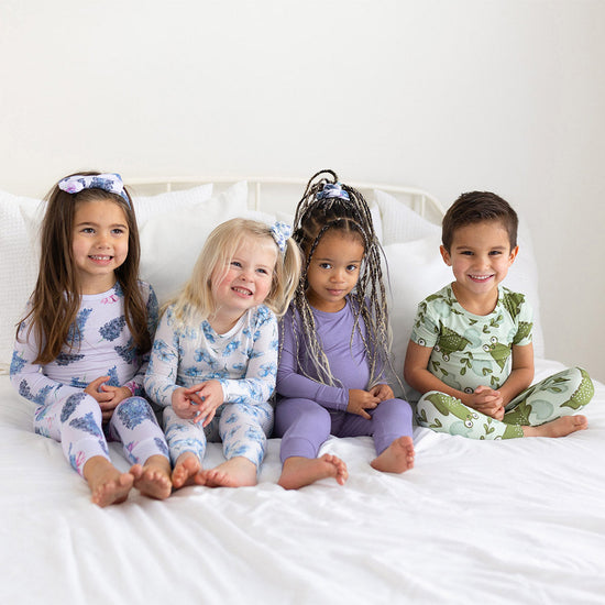 4 children in pajamas on a bed