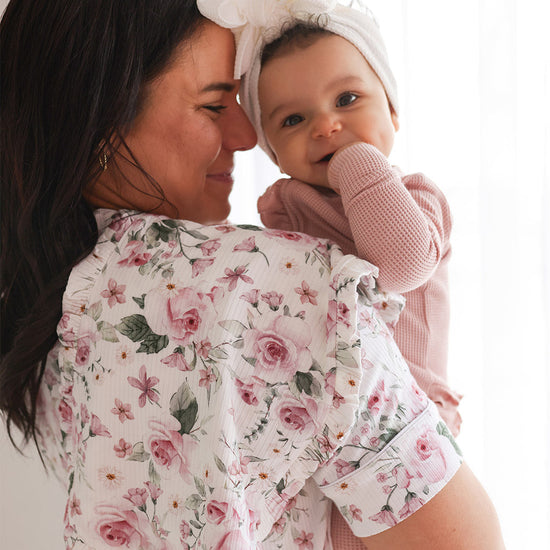 mother wearing floral print blouse holding child