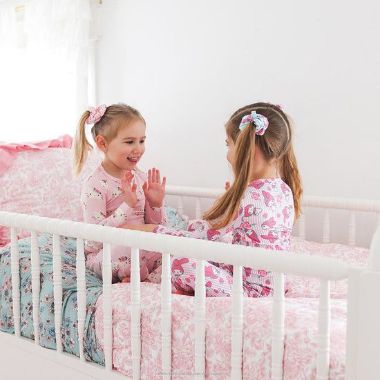 two girls sitting in a bed 