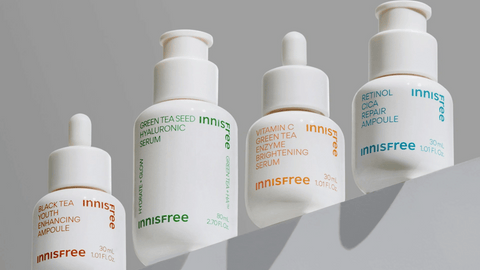 Bild av fyra olika serum från Innisfree snyggt placerade på en hylla, fotograferade underifrån. Produkterna ger intrycket av mångsidig hudvård och en stilfull presentation.