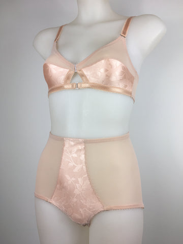 faux vintage inspired longline girdle and front fastening bralette in peachy floral satin fabric. Longline girdle has 6 beige suspender clips holding up seamed nylon stockings. Matching garter belt, longline underwired bra and pantie girdle . Longline girdle has 6 beige suspender clips holding up seamed nylon stockings. Matching garter belt, longline underwired bra and pantie girdle 