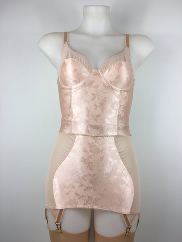 faux vintage inspired longline girdle and front fastening bralette in peachy floral satin fabric. Longline girdle has 6 beige suspender clips holding up seamed nylon stockings. Matching garter belt, longline underwired bra and pantie girdle 