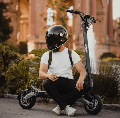 man sitting on apollo electric scooter wearing helmet