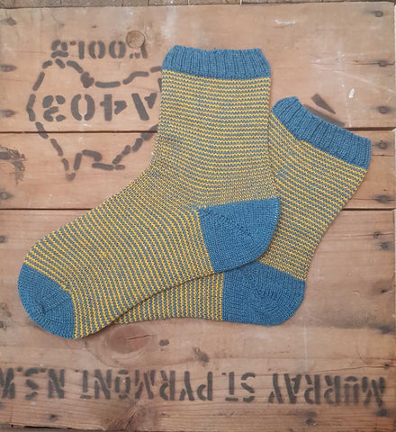 A pair of teal and gold stripy hand knitted socks in Regia Premium Silk