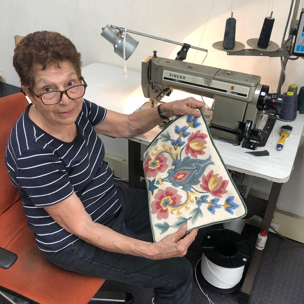 Mrs Morris sitting at her Singer sewing machine showing off a tapestry being transformed into a cushion