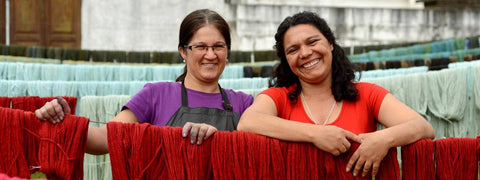 Two women standing behind hand dyed yarn drying