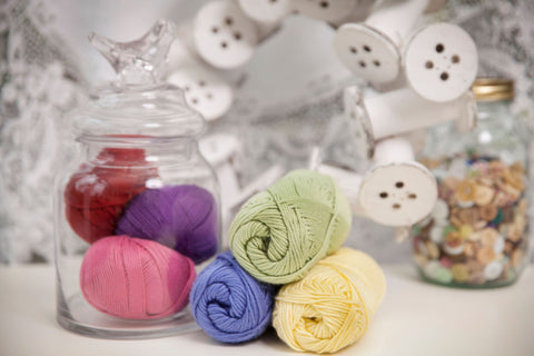 Selection of Rowan cotton knitting yarns displayed in jars with buttons