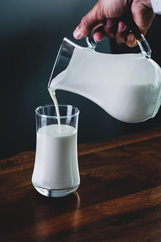 pouring milk from a jug to a cup