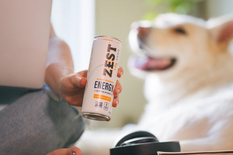 woman holding cold energy tea near a dog