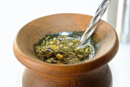 yerba mate leaf in a wooden cup with a straw