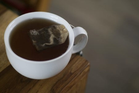 cup of black tea with a teabag brewing