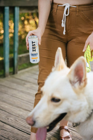 woman drinking energy tea while walking the dog