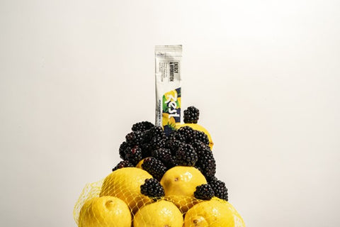 electrolyte powder stick balanced on a mound of lemons and blackberries