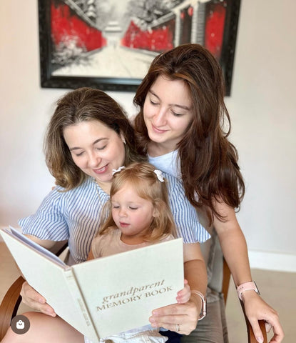 Mom reading a memory book to her daughters