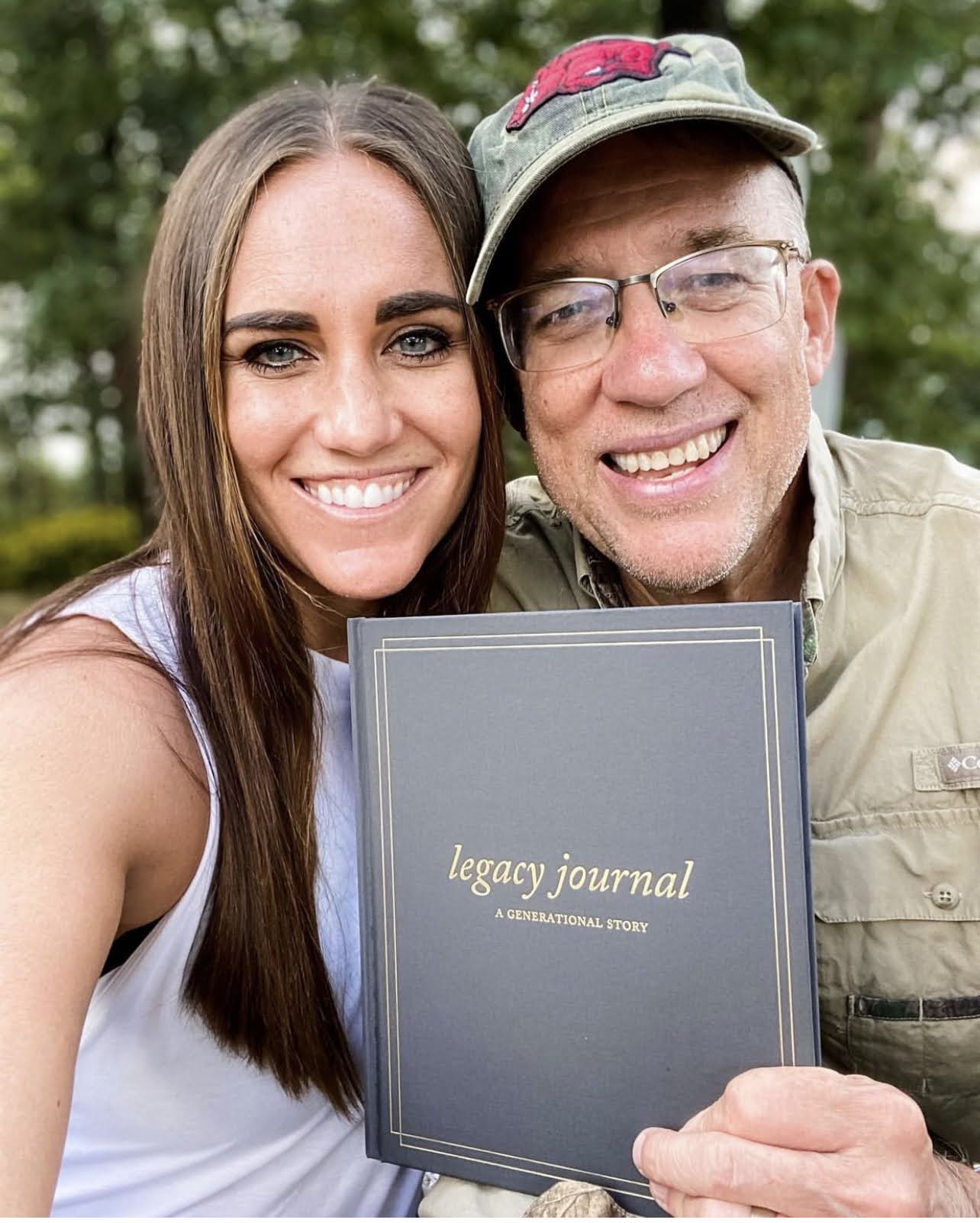 2 people smiling and holding a legacy journal