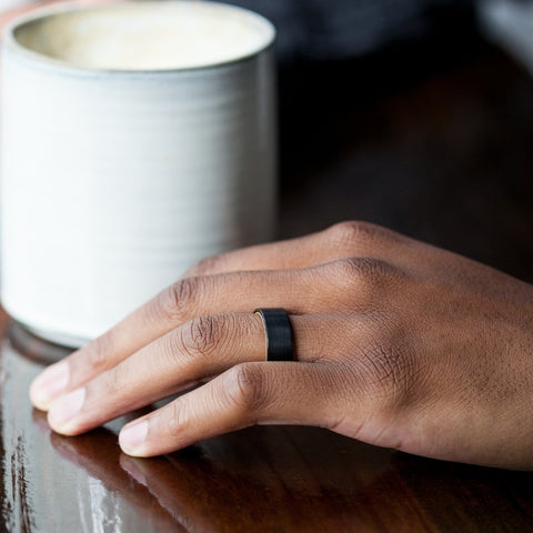 coffee cup with a man's hand next to it with a wedding ring