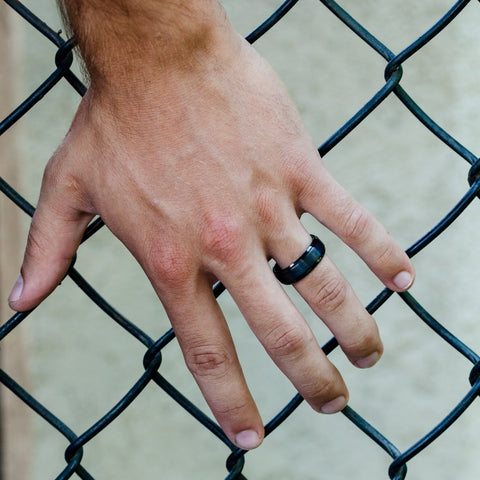 mans hand on a fence with wedding band on