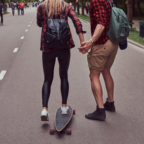 man holding a women's hands while skateboarding