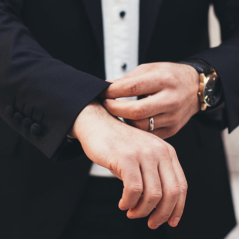 groom in suit touching sleeve