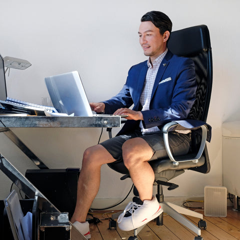 man sitting at desk with slippers and a blazer