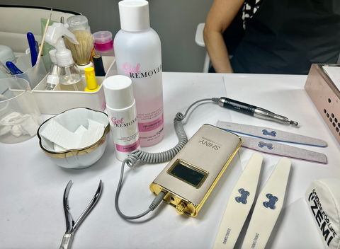 Table set up with nail tools and accessories, with a nail technician showing different tools like an electric file.