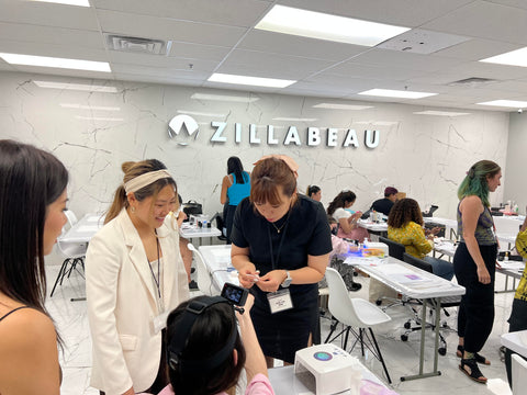 A nail art educator reviewing the nails of a student, while a translator watches on.