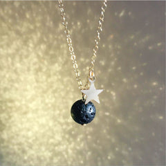 A moon and star necklace on a glittering gold background