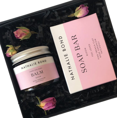 A glass jar of hand balm and a natural soap bar in a gift box