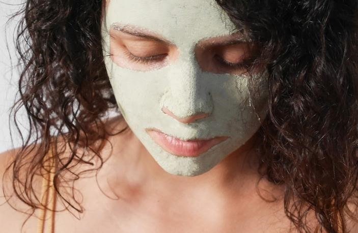 Woman applying a natural clay face mask